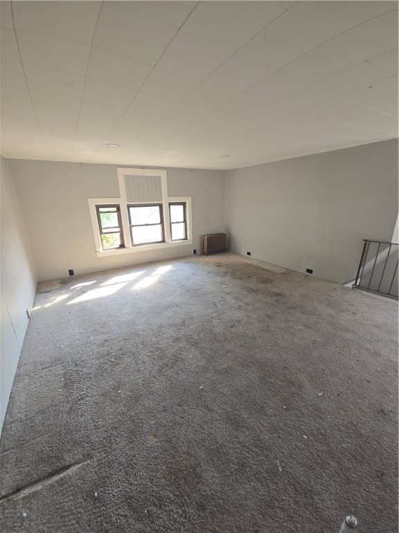 unfurnished room featuring radiator heating unit and carpet flooring