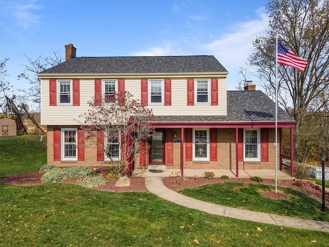 colonial inspired home featuring a porch and a front yard