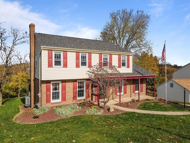 colonial-style house with central air condition unit, covered porch, and a front lawn