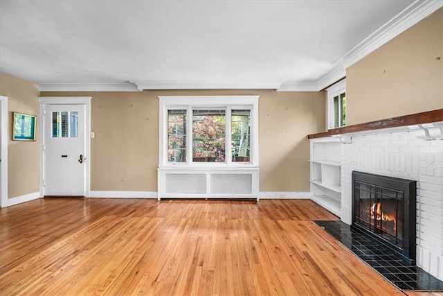 unfurnished living room with light hardwood / wood-style floors, crown molding, radiator heating unit, and a fireplace