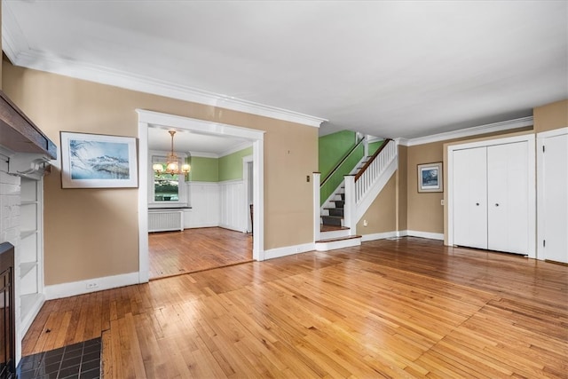 unfurnished living room featuring radiator, wood-type flooring, ornamental molding, and a chandelier