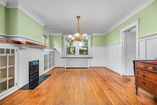 unfurnished dining area with light hardwood / wood-style flooring, radiator heating unit, a chandelier, and crown molding