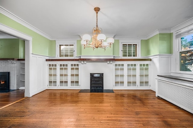 interior space with a notable chandelier, hardwood / wood-style flooring, and a brick fireplace