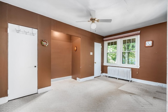 carpeted empty room featuring radiator and ceiling fan