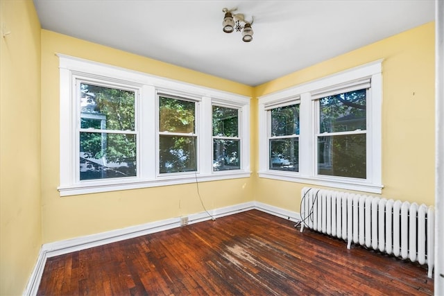 unfurnished room featuring dark wood-type flooring and radiator heating unit