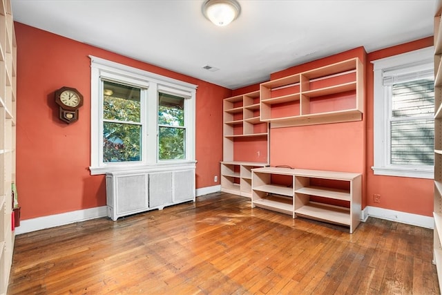 unfurnished office featuring hardwood / wood-style floors and radiator