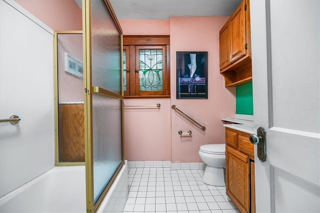 full bathroom with vanity, bath / shower combo with glass door, toilet, and tile patterned floors