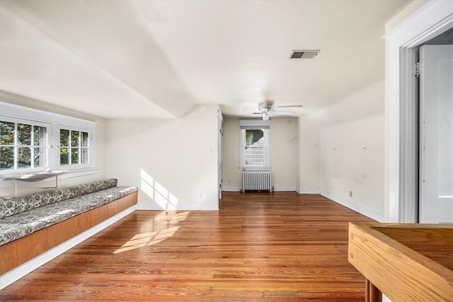 unfurnished living room with radiator, ceiling fan, and wood-type flooring