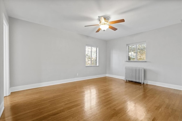 unfurnished room featuring radiator heating unit, wood-type flooring, and ceiling fan