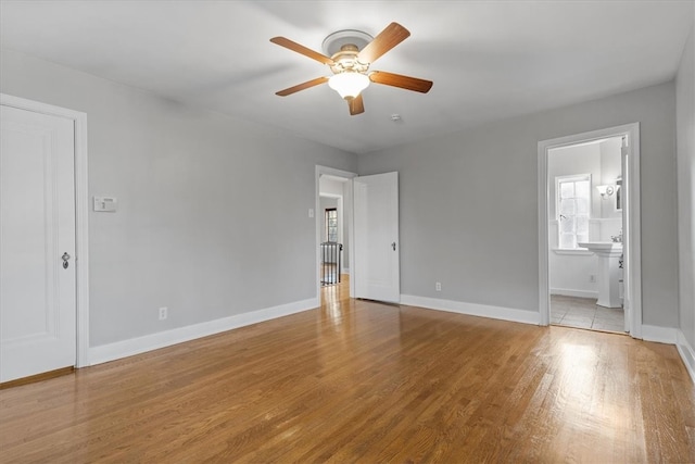 unfurnished bedroom featuring ensuite bathroom, light wood-type flooring, and ceiling fan