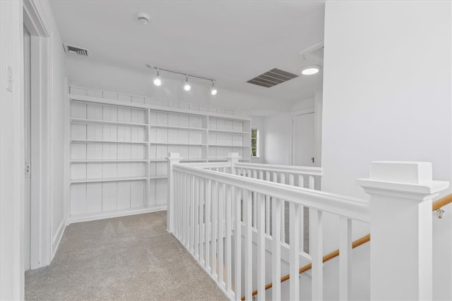 hall with light colored carpet and track lighting