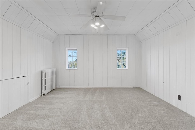 additional living space with wood walls, lofted ceiling, a healthy amount of sunlight, and radiator