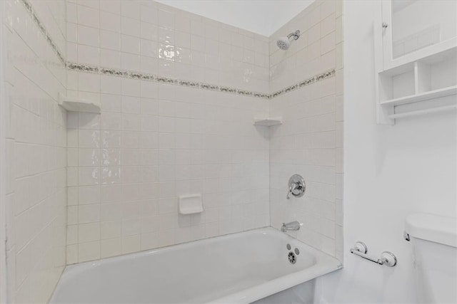 bathroom with toilet and tiled shower / bath