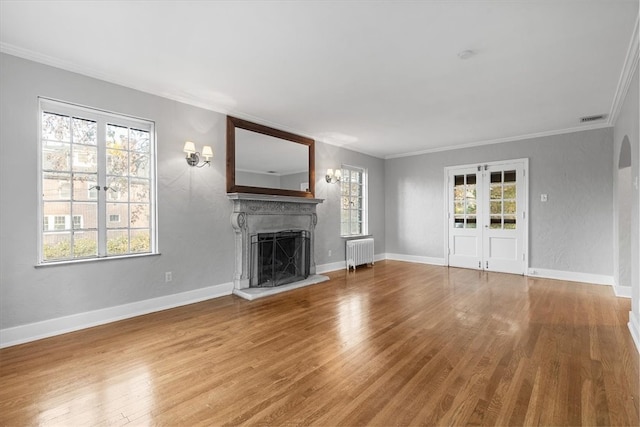 unfurnished living room featuring a wealth of natural light, radiator heating unit, and hardwood / wood-style flooring