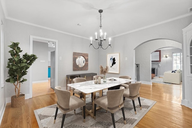 dining area with ornamental molding, a chandelier, and light hardwood / wood-style floors