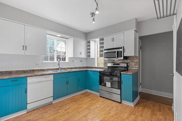 kitchen with blue cabinetry, appliances with stainless steel finishes, sink, and white cabinets