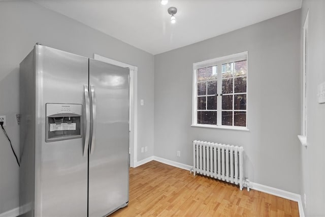 kitchen with stainless steel refrigerator with ice dispenser, radiator heating unit, and light wood-type flooring