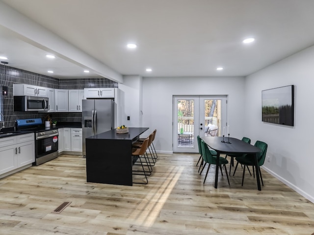 kitchen featuring a breakfast bar, light wood-type flooring, white cabinetry, and appliances with stainless steel finishes