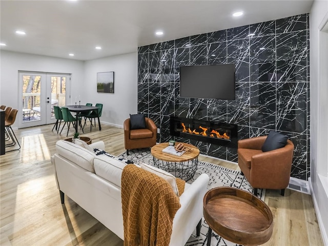 living room featuring a high end fireplace, wood-type flooring, french doors, and tile walls