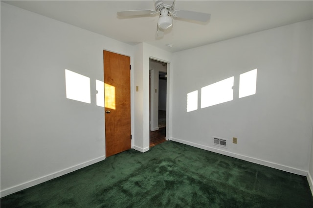 empty room featuring a wealth of natural light, dark colored carpet, and ceiling fan