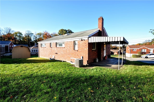 view of home's exterior featuring central AC, a storage unit, a lawn, and a carport