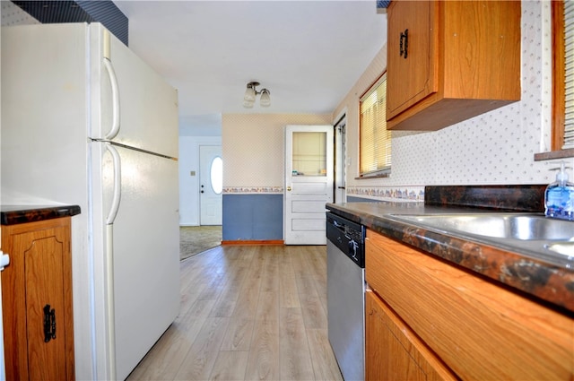 kitchen featuring light wood-type flooring, stainless steel dishwasher, and white refrigerator