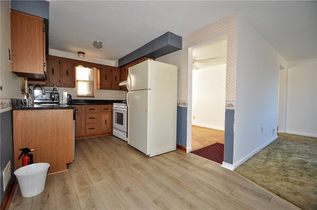 kitchen featuring white appliances, range hood, sink, and light wood-type flooring