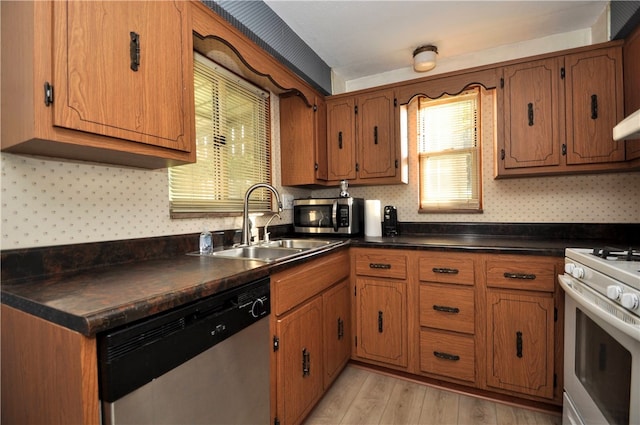 kitchen with sink, appliances with stainless steel finishes, and light hardwood / wood-style flooring