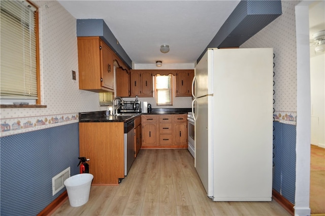 kitchen with appliances with stainless steel finishes, sink, and light wood-type flooring