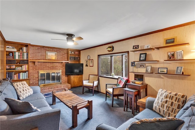 living room featuring dark colored carpet, crown molding, a brick fireplace, built in shelves, and ceiling fan