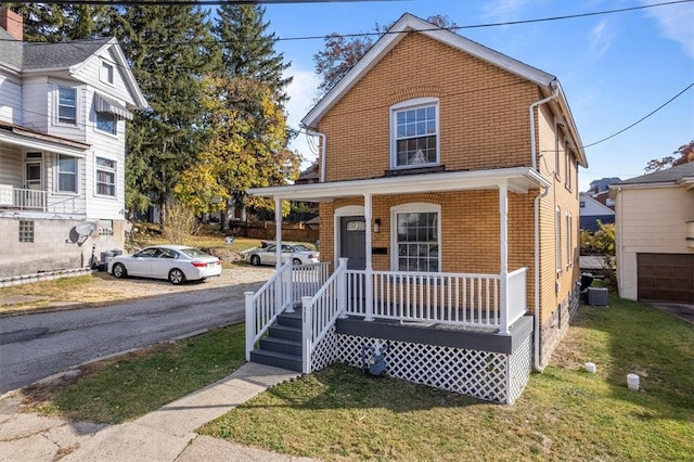 view of property with a front yard, a porch, and a garage