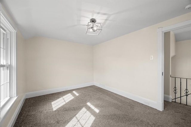 empty room featuring vaulted ceiling and carpet floors