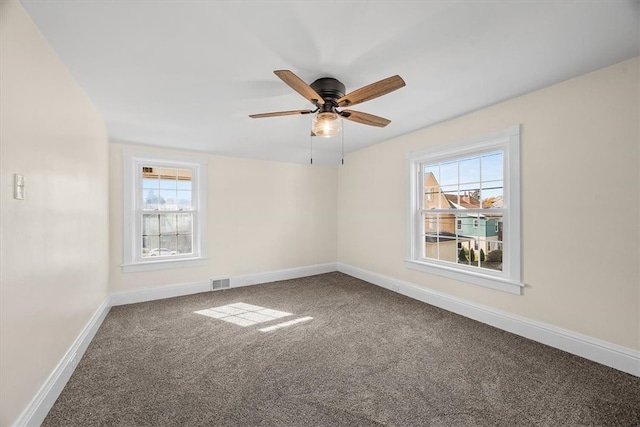 carpeted spare room featuring a healthy amount of sunlight and ceiling fan