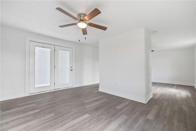 empty room featuring a ceiling fan, baseboards, and wood finished floors