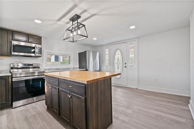 kitchen featuring light wood-type flooring, butcher block countertops, stainless steel appliances, and a healthy amount of sunlight