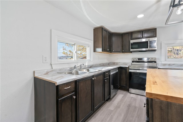 kitchen featuring appliances with stainless steel finishes, sink, light wood-type flooring, butcher block counters, and dark brown cabinets