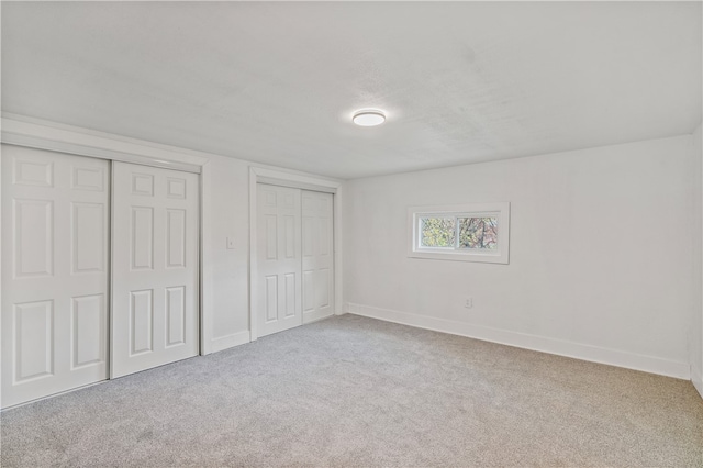 unfurnished bedroom featuring two closets and light colored carpet