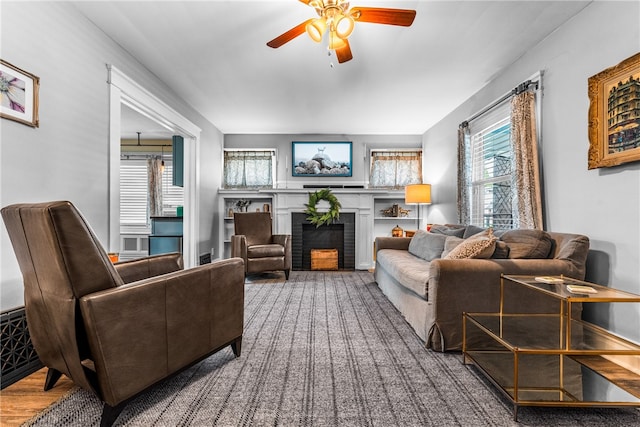 living room featuring hardwood / wood-style floors, ceiling fan, and a brick fireplace