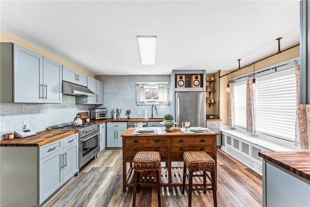 kitchen featuring wooden counters, hardwood / wood-style floors, a kitchen breakfast bar, and stainless steel appliances