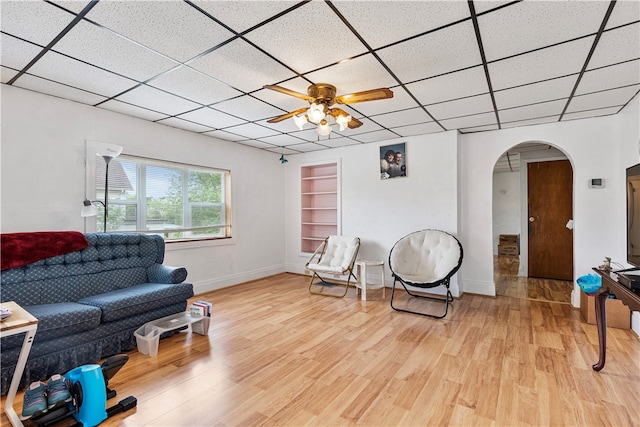 living room featuring a paneled ceiling, ceiling fan, and light wood-type flooring