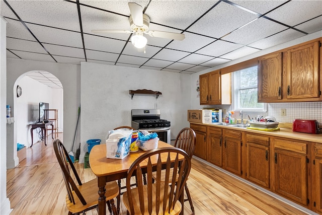 kitchen featuring light hardwood / wood-style flooring, ceiling fan, gas stove, and a paneled ceiling