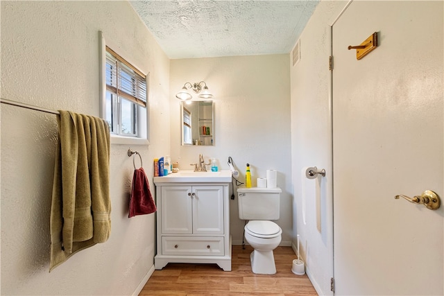 bathroom featuring vanity, hardwood / wood-style floors, toilet, and a textured ceiling