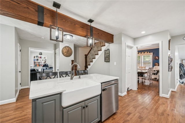 kitchen with light stone countertops, light wood-type flooring, hanging light fixtures, stainless steel dishwasher, and gray cabinets