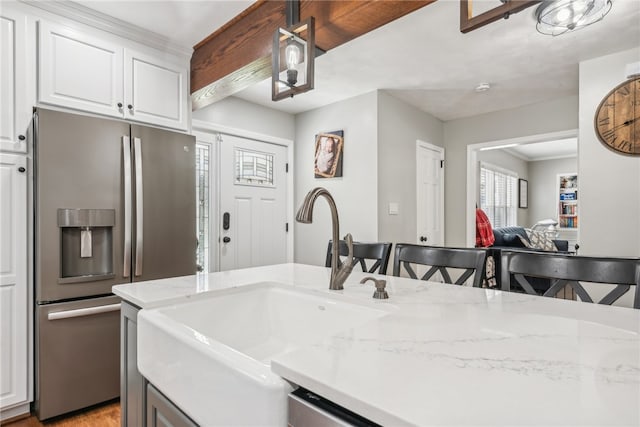 kitchen featuring sink, stainless steel fridge with ice dispenser, white cabinets, light stone counters, and a breakfast bar