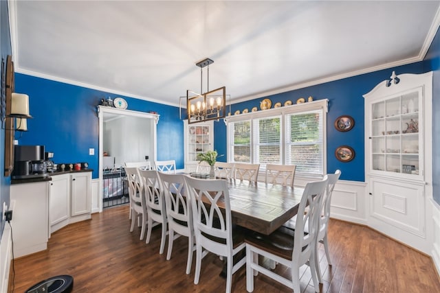 dining area featuring dark wood-type flooring, crown molding, and an inviting chandelier