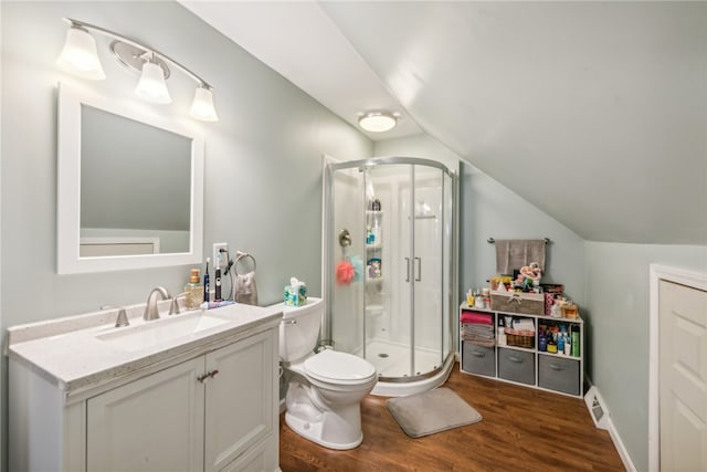 bathroom featuring toilet, hardwood / wood-style floors, vaulted ceiling, vanity, and walk in shower