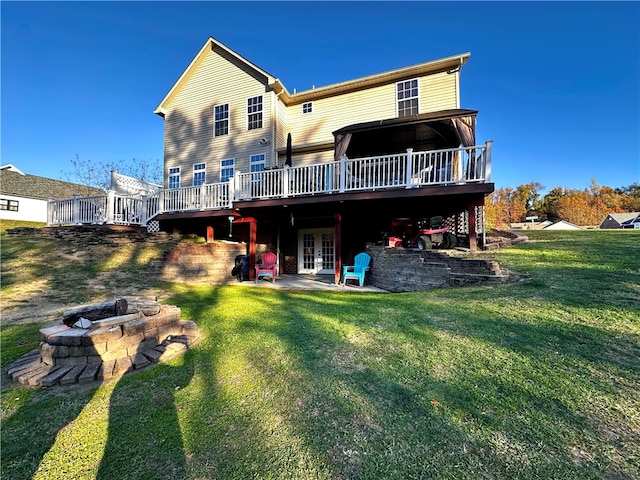 rear view of house featuring a wooden deck, a patio, an outdoor fire pit, and a yard