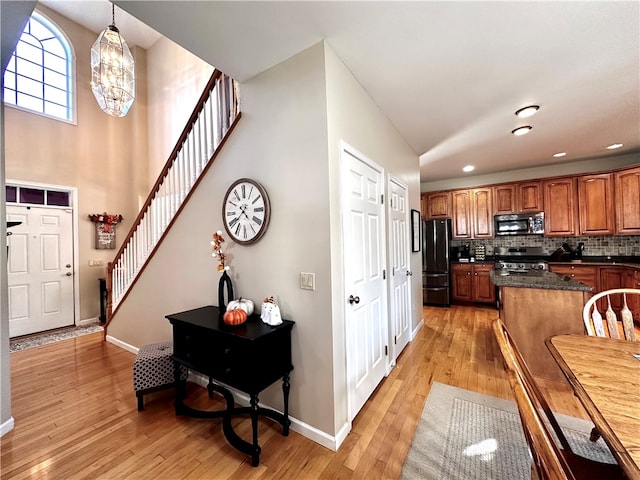 kitchen featuring tasteful backsplash, hanging light fixtures, an inviting chandelier, light hardwood / wood-style floors, and stainless steel appliances