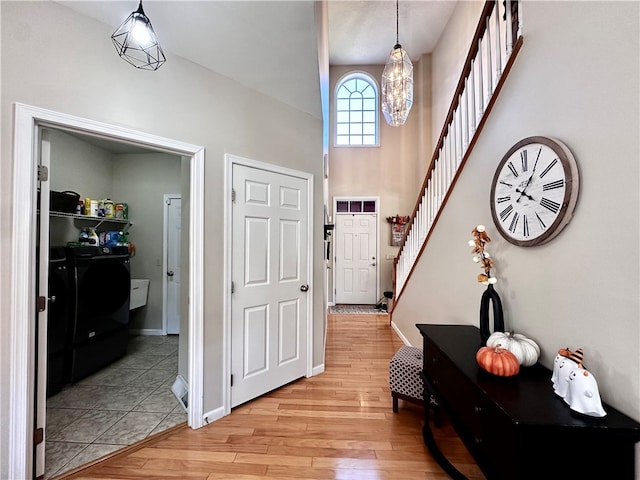 entrance foyer featuring light hardwood / wood-style flooring, a notable chandelier, and washer and clothes dryer