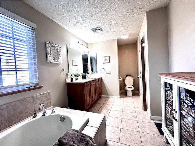 bathroom with a bath, a textured ceiling, toilet, tile patterned floors, and vanity